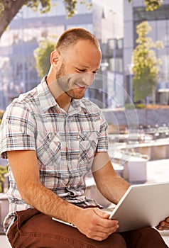 Happy man with laptop outdoors