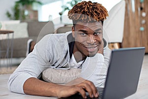 happy man laying down on floor using laptop