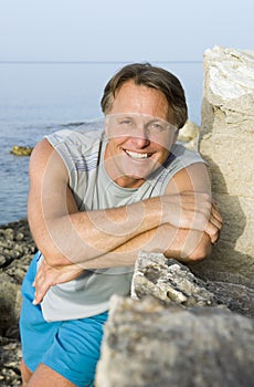 Happy man leaning on a rock