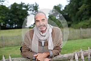 Happy man leaning on wood fence