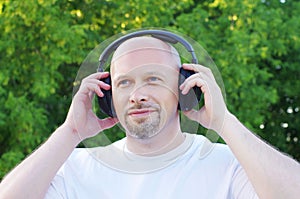 Happy man listening music outdoors in wireless headset