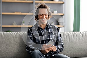 Happy Man Listening To Music On Phone Sitting At Home