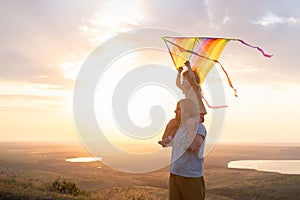 Happy man and little boy, father and sons, with kite in nature at sunset