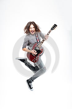 Happy man with long hair jumping and playing electric guitar