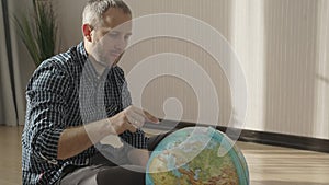 Happy man looking at globe, exploring new countries for travel