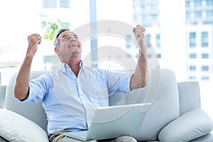 Happy man looking up while working on laptop