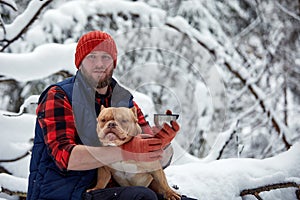 Happy man with lovely dog in snowy forest. Smiling boy going adorable puppy in winter wood. Pet lover. Dog - human s