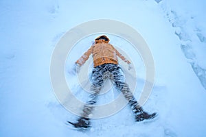 Happy man lying down on the snow in winter