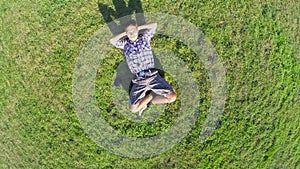 Happy man lying on grass hands behind head, aerial shot