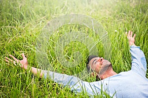 Happy man lying on the green grass with arms outstretched photo