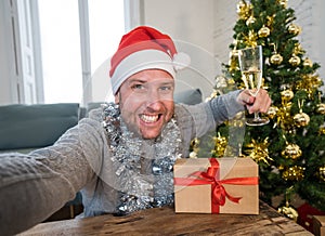 Happy man with mobile phone on video call celebrating christmas with family at home in lockdown