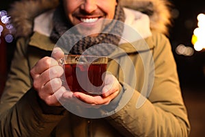 Happy man with mulled wine at winter fair, closeup