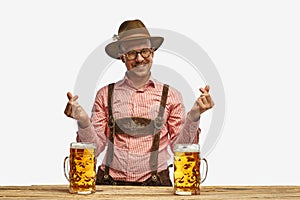 Happy man with mustaches wearing traditional german outfit with beer showing heart symbol, shape feelings. Concept of