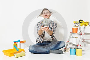 Happy man in newspaper hat holds bundle of dollars, cash money. Instruments for renovation apartment isolated on white