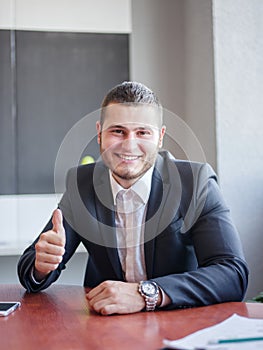 Happy man in the office sitting and posing on the camera . Business concept.