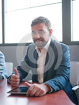 Happy man in the office sitting and posing on the camera . Business concept.