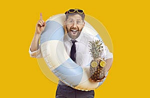 Happy man office wear, sun glasses with rubber inflatable ring, tropic fruit in summer holiday dream