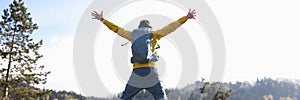 Happy man with open arms jumping, lake and mountains in background.