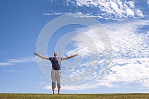 Happy man with open arms standing on green field