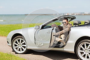 Happy man opening door of cabriolet car outdoors