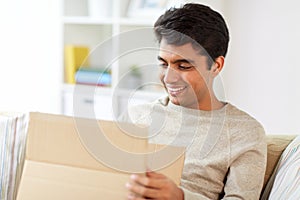 Happy man opening parcel box at home