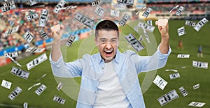 happy man with over money rain on football field