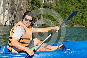 Happy man paddling a kayak on the ocean