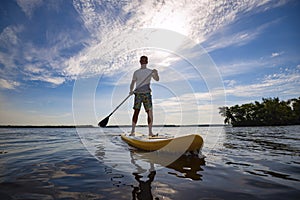 Happy man is paddling on a SUP board
