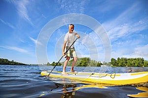 Happy man is paddling on a SUP board