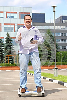 Happy man with phone thumbs up on GyroScooter near photo