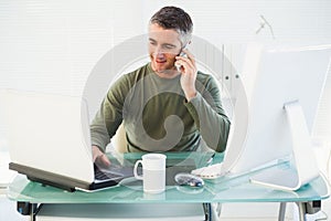 Happy man phoning and using laptop