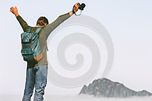 Happy man photographer traveling in mountains success raised arms