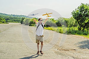Happy man playing with toy airplane against old runway background. Traveling with kids concept