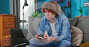 Happy man playing video games in apartment - Hilarious teenager boy having fun with new