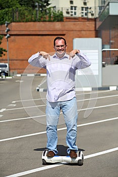 Happy man points to GyroScooter on street at sunny photo