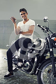 Happy man, portrait and keys sitting on motorcycle keys for transportation or vehicle in garage. Young male person or