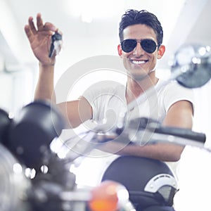 Happy man, portrait and motorcycle keys with helmet and sunglasses for transportation vehicle in garage. Young male