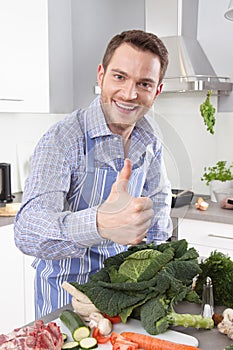 Happy man posing with vegetables in the kitchen - thumbs up
