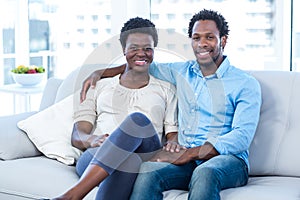 Happy man with pregnant wife sitting at home