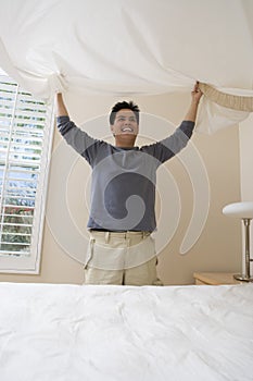 Happy Man Preparing Bed At Home