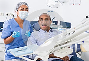 Happy man with professional woman stomatologist in dental clinic