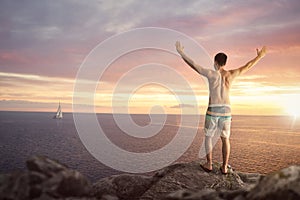 Happy man with raised arms on top of a sea cliff