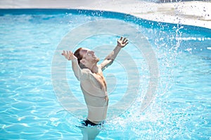 Happy man with raised up hands in water inpool