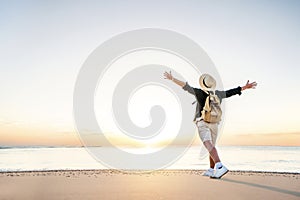 Happy man raising arms up on the beach at sunset - Delightful man enjoying peaceful moment walking outdoors