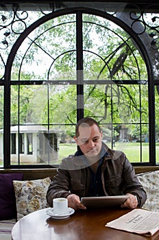 A happy man reading an ebook in a coffee shop