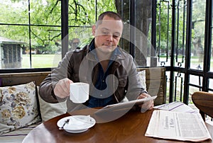 A happy man reading an ebook in a coffee shop