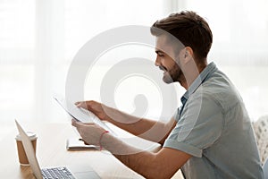 Happy man reading letter sitting at the desk