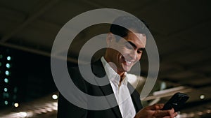 Happy man reading phone message crossing night close up. Smiling manager walking