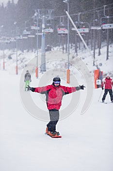 Šťastný muž v červené bundě na snowboard skiin na hoře. Sněží