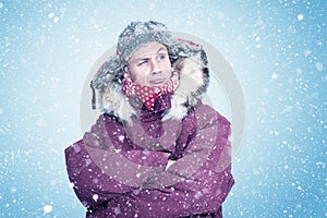 Happy man in red winter clothes warms his hands, cold, snow, frost, blizzard photo